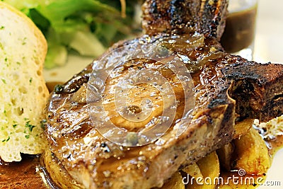 High resolution grilled `kuro buta`pork ribs and black pepper sauce served with potato wedges,bread and salad Stock Photo