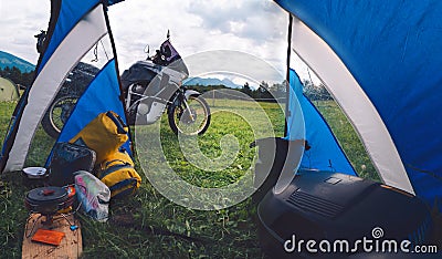 High resolution panorama. View from camp tent door. Motorcycle adventure bike on the background of green grass, forest and Stock Photo