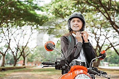 High school girl tightens helmet strap while riding motorbike Stock Photo