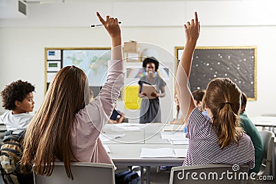 High School Students Raising Hands To Answer Question Set By Teacher In Classroom Stock Photo