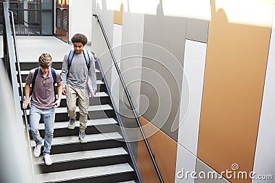 High School Students Walking Down Stairs In Busy College Building Stock Photo