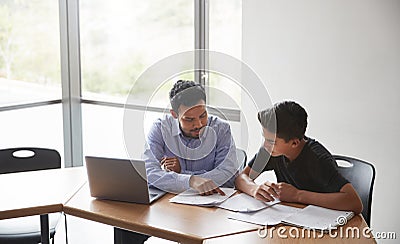 High School Tutor Giving Male Student With Laptop One To One Tuition At Desk Stock Photo