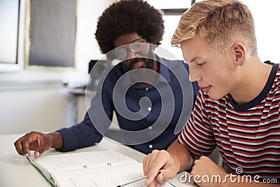 High School Tutor Giving Male Student One To One Tuition At Desk In Classroom Stock Photo