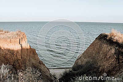 High seashore overgrown with tall grass and meadow plants. Sandy cliffs over the sea. Stock Photo