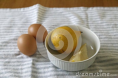 High shot of lemons inside a white bowl with 2 organic eggs Stock Photo