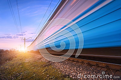 High speed blue passenger train in motion on railroad Stock Photo