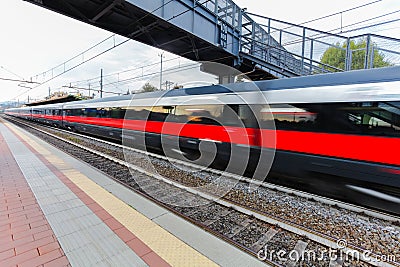 High speed passenger trains on railroad platform in motion. Blur effect of commuter train. Railway station in Florence, Italy. Stock Photo