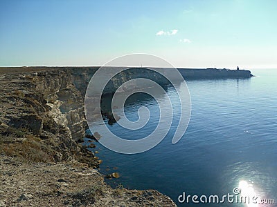 High steep coastal long rocky cliff with a building at the end. Stock Photo