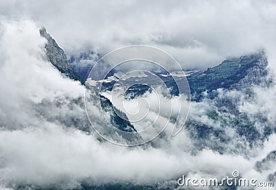 High and steep mountain surrounded by heavy clouds Stock Photo