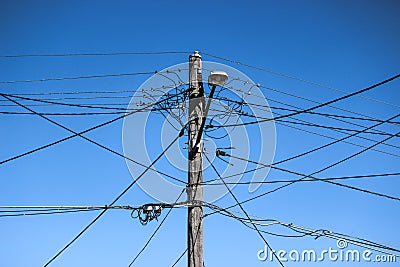 High voltage electricity pole with complex wiring, street lamp and blue sky Stock Photo