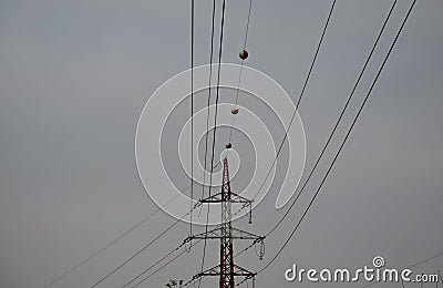 The high voltage poles are painted white and red stripes. The plastic balls on the wires are used as a safety feature to highlight Stock Photo