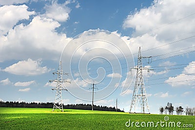 High-voltage power lines in green field against blue sky with white clouds. Power line in green meadow. Stock Photo