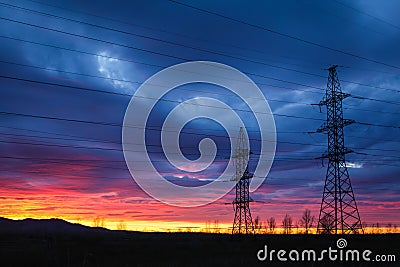 High voltage power tower and silhouette power lines at sunset Stock Photo