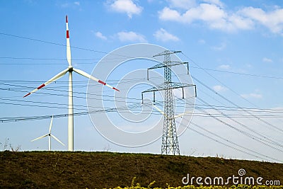 High voltage tower and wind turbines against blue sky Stock Photo