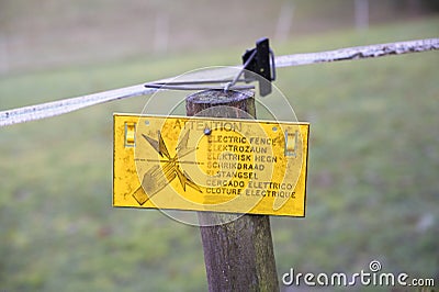 High voltage yellow danger sign farm field fence Stock Photo