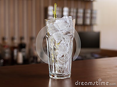 Highball glass with ice and a yellow tube on the wooden bar Stock Photo