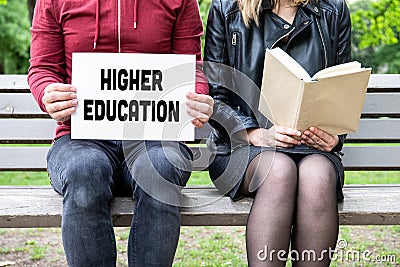 Higher Education concept. Cpuple on a bench at the park, woman reads a book Stock Photo