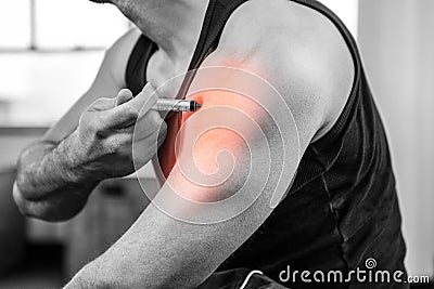 Highlighted arm of strong man injecting anabolic steroid at gym Stock Photo