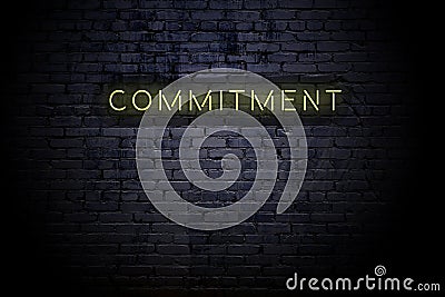 Highlighted brick wall with neon inscription commitment Stock Photo