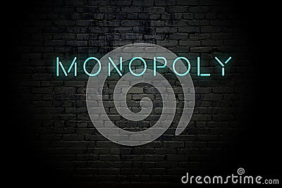 Highlighted brick wall with neon inscription monopoly Stock Photo