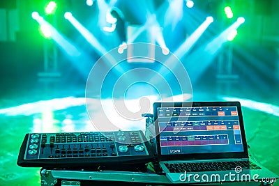 Highlighted deejay mixing with laptop on the stage with blue beams and lightshow Editorial Stock Photo