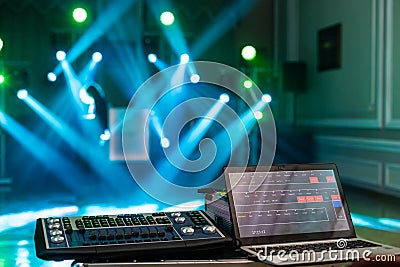 Highlighted deejay mixing with laptop on the stage with blue beams and lightshow Stock Photo