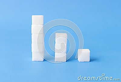 Hight to low stacks of sugar cubes with blue background, health Stock Photo