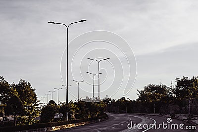 Highway curve road overpass nature landscape background dark tone mist day time street tall lanterns trees bushes Stock Photo