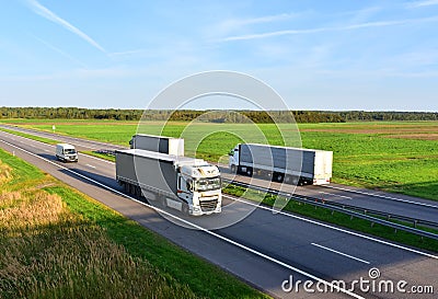 Highway with Lots of semi-trailer trucks . Big lorry traffic on the road. Truck driving along on roadway overtakes another truck. Editorial Stock Photo
