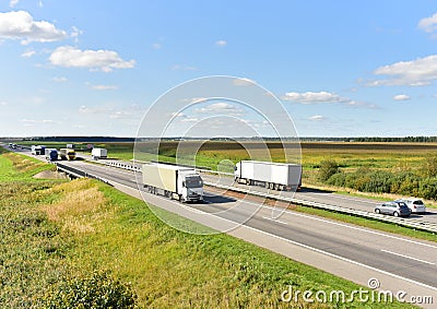 Highway with Lots of semi-trailer trucks . Big lorry traffic on the road. Truck driving along on roadway overtakes another truck. Editorial Stock Photo