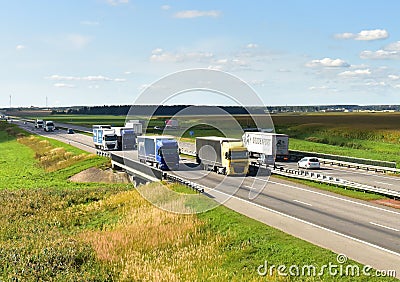 Highway with Lots of semi-trailer trucks . Big lorry traffic on the road. Truck driving along on roadway overtakes another truck. Editorial Stock Photo