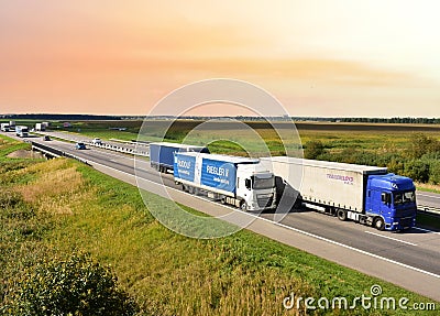 Highway with Lots of semi-trailer trucks . Big lorry traffic on the road. Truck driving along on roadway overtakes another truck. Editorial Stock Photo