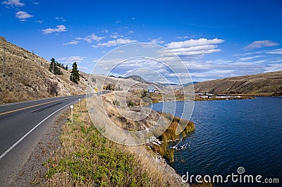 Highway skirting a scenic mountain lake Stock Photo