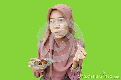 hijab muslim woman eating dates during iftar with green background Stock Photo