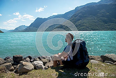 hiker with backpack resting near Gjende lake in Jotunheimen National Stock Photo