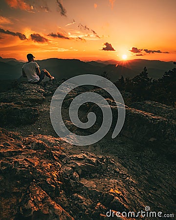 Hiker with backpack sitting on mountain and enjoying sunset Editorial Stock Photo