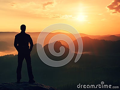 Hiker in black stand on the peak in rock empires park and watching over the misty and foggy morning valley to Sun. Beautiful mome Stock Photo