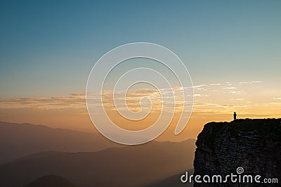 Hiker on the Edge of a Remote Mountain at Sunrise Stock Photo