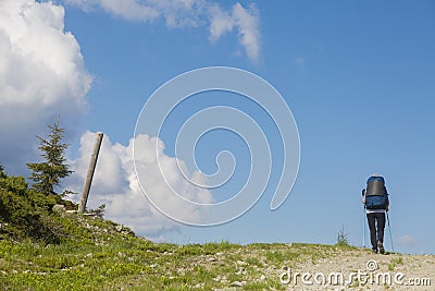 Hiker follows a path, the blue sky on the horizon. Hiking travel outdoor concept in mountains Stock Photo