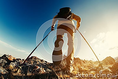 Hiker goes with trekking poles uphill Stock Photo