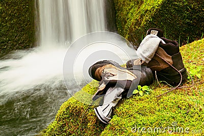Hiker high boots and sweaty grey socks. Resting on the mossy boulder at the nice mountain stream Stock Photo