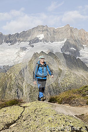 Hiker hikes through a breathtaking alpine landscape in the mountains Stock Photo