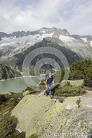 Hiker hikes through a wild high alpine landscape with a lake Stock Photo