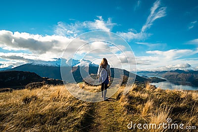 A hiker hiking on the beautiful track with a landscape of the mountains and Lake Wanaka. Roys Peak Track, South Island, New Editorial Stock Photo