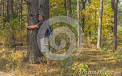 Hiker leans to a tree beeing charging by positive nergy Stock Photo