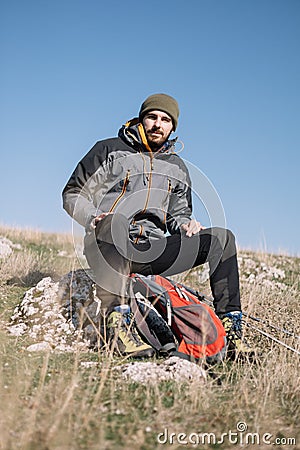 Hiker male sitting on a rock on top of the mountain Stock Photo