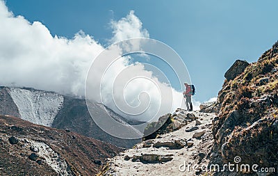 Hiker man silhouette on clouds background standing on path going over the Imja Khola valley and enjoying mountain views during an Stock Photo