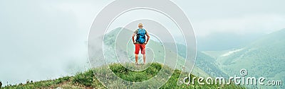 Hiker man walking by the cloudy and foggy weather mountain range path with backpack. Active sport backpacking healthy lifestyle Stock Photo