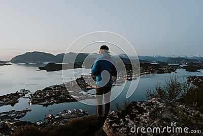 Hiker is observing picturesque norwegian city scenery from the mountain. Travel and hiking concept Stock Photo