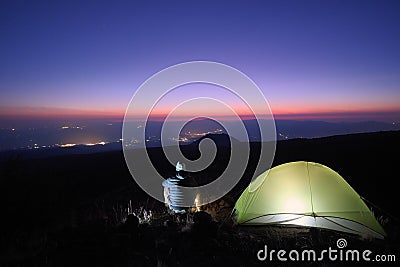 Hiker Overlooking Town Lights From Wild Camp At Twilight Stock Photo